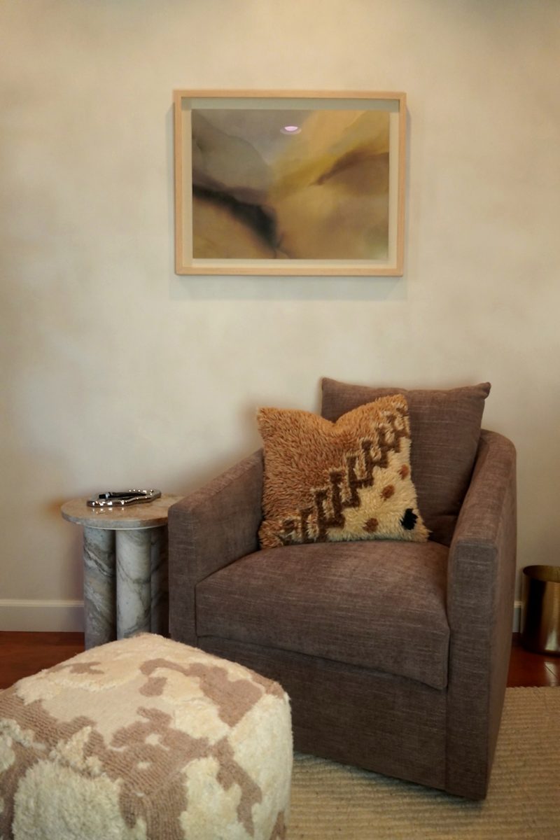 Linen armchair with a textured wool pillow next to a marble pedestal side table.
